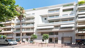 Un edificio de varios pisos con balcones, un paso de peatones y una camioneta estacionada.