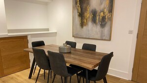 A dining area with a wooden table and black chairs, a small decorative vase, and a large abstract painting on the wall. - Apartment 2 (York)