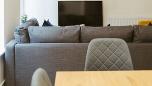 A modern living room with a grey sofa, a wooden table, and a television. - Apartment 1 (York)