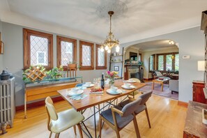 A dining area with a wooden table set for four, surrounded by chairs, with a chandelier above. - Ferndale Gem, Walk to Stores & Restaurants! (Ferndale)