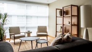 Een moderne woonkamer met een bank, twee fauteuils, een salontafel en een boekenkast.