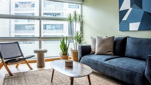 Ein modernes Wohnzimmer mit einer Couch, einem Couchtisch, einem Sessel und zwei Zimmerpflanzen.
