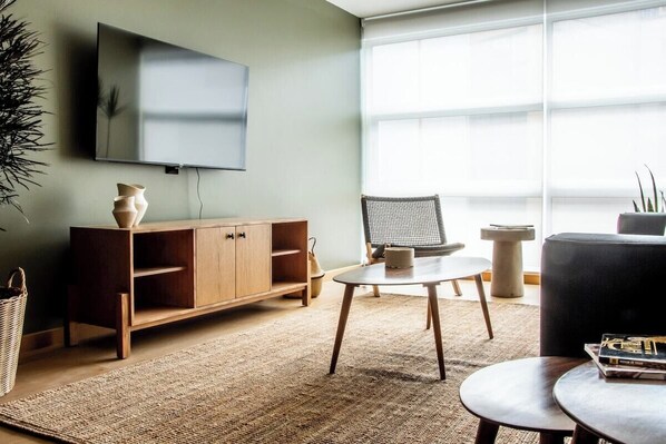 A modern living room with a TV, wooden cabinet, wicker chair, and a round coffee table. - Great location, pool, rooftop, gym, 24/7 security (Ciudad de México)