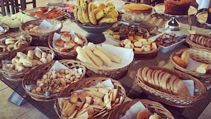 Una mesa de buffet con panes, pasteles y frutas variados.