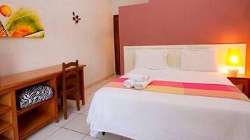 Ein Hotelzimmer mit Bett, Schreibtisch, Stuhl und Wandlampe.