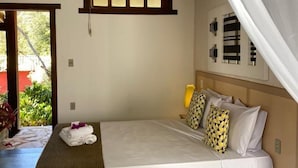 Un dormitorio con cama, ventana, mesita de noche y cortina.