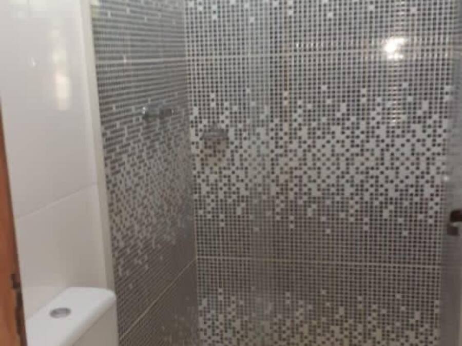 A bathroom with a toilet, shower, and tiled walls.