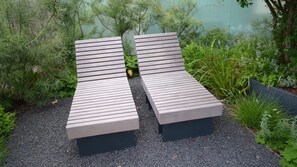 Relax in comfortable lounge chairs surrounded by lush greenery and a serene water view.