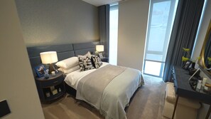 Relax in a spacious room with a large bed, two bedside tables, and a desk with a mirror.