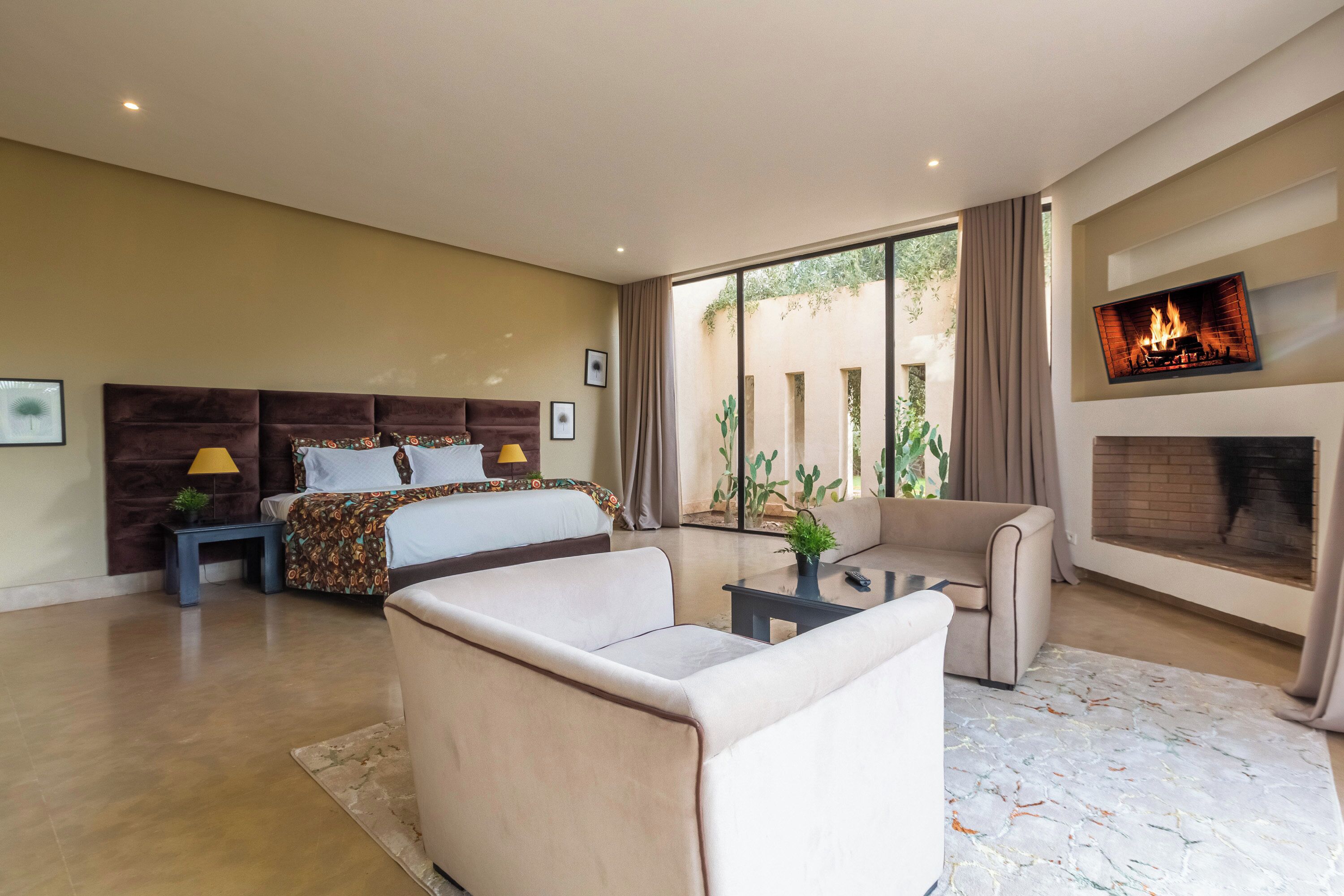 A spacious bedroom with a large bed, a sofa, and a fireplace.