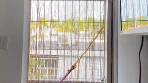 An air conditioning unit with a digital display, a window with a bamboo screen and a hammock, and a view of the outside. - Quiet accommodation 15 minutes away from the airport. Apartment 1 (Trujillo Alto)