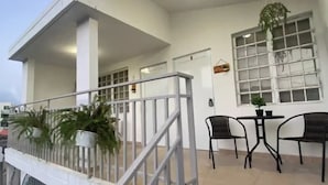 A hotel with a balcony, a staircase, and a dining area with chairs and a table. - Quiet accommodation 15 minutes away from the airport. Apartment 1 (Trujillo Alto)
