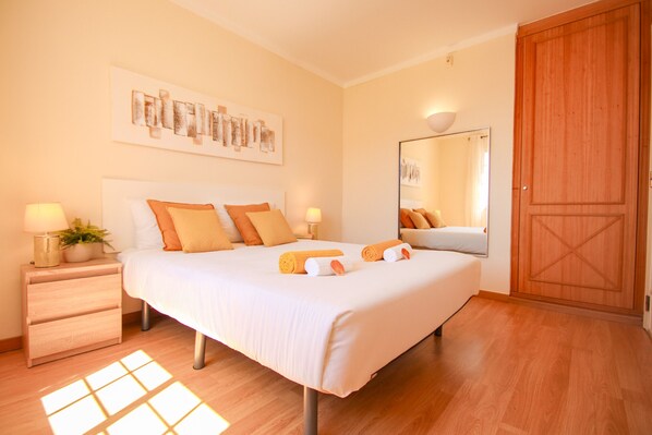 Een hotelkamer met een bed, nachtkastjes, een spiegel en een houten kledingkast.