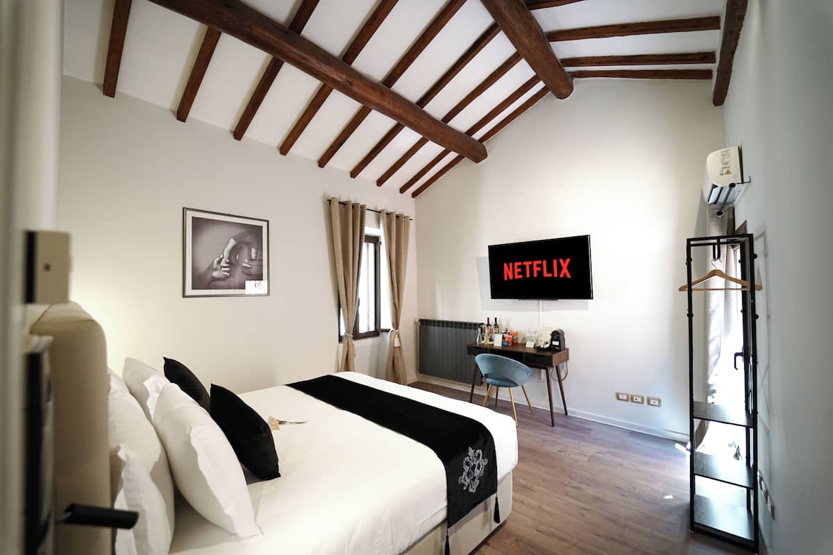 Ein Schlafzimmer mit Bett, Schreibtisch, Sessel, Fernseher und Kleiderschrank.