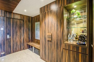 A modern hotel lobby with wooden paneling, a bench, a glass display case with water bottles, and a coffee machine.