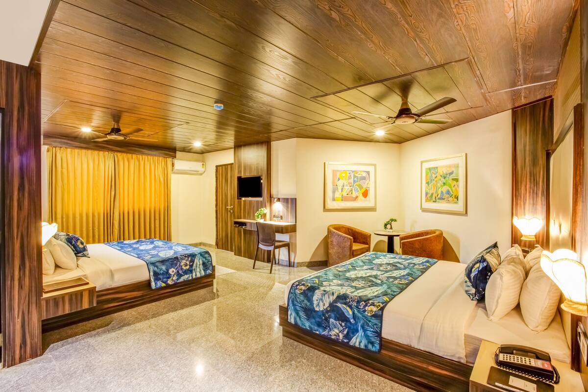 Habitació d'hotel amb dos llits, una taula de treball, una cadira i un ventilador de sostre.