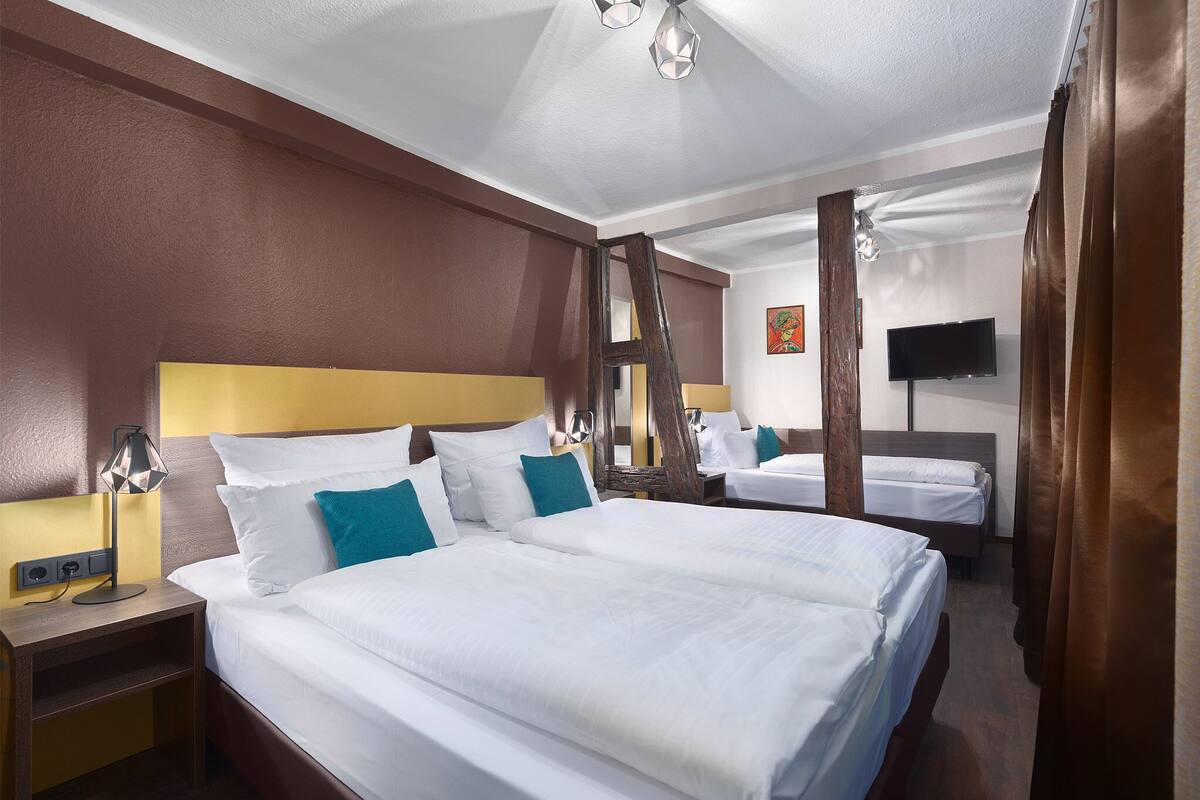 A hotel room with two beds, a TV, and a mirror.