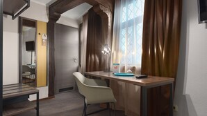 Una habitación moderna con un escritorio de madera, una silla, un televisor y una ventana con cortinas.