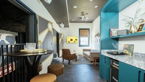 A modern kitchen with teal cabinetry, a marble countertop, and a built-in Marshall amplifier.