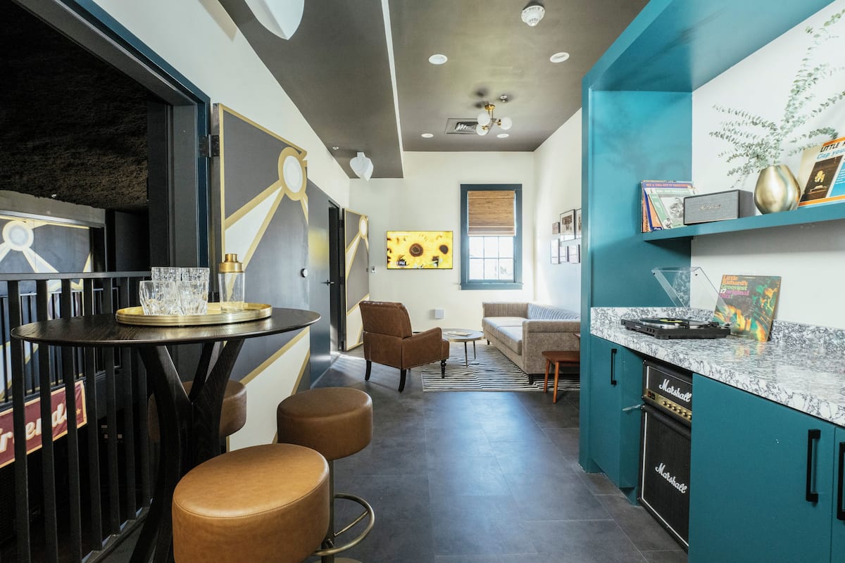 A modern kitchen with teal cabinetry, a marble countertop, and a built-in Marshall amplifier.