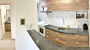 Una cocina con armarios de madera, un microondas, una estufa y un lavabo.
