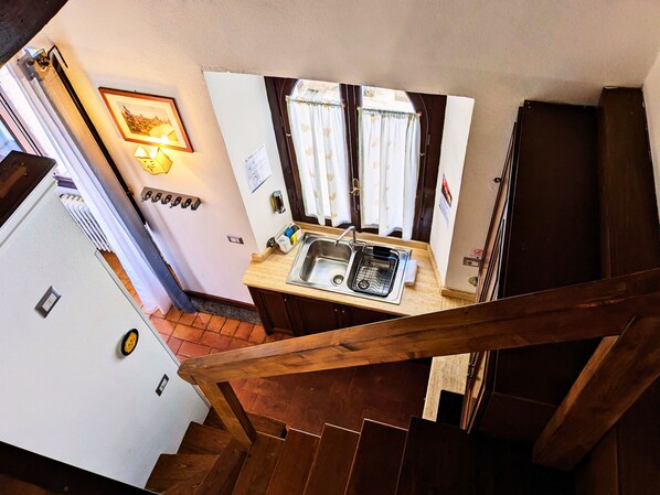 A kitchen with a sink, a window with curtains, and a refrigerator. - Elegance in Rome's Heart - Smart Lodging Prime (Roma)