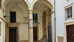 A courtyard with a herringbone-patterned floor, arched doorways, and a column. - Elegance in Rome's Heart - Smart Lodging Prime (Roma)