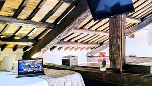 A bedroom with a bed, a laptop, a flat-screen TV, and a flower vase. - Elegance in Rome's Heart - Smart Lodging Prime (Roma)