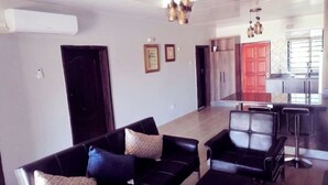 Ein modernes Wohnzimmer mit schwarzen Ledersofas, einem Essbereich und einer Küche mit roten Schränken.