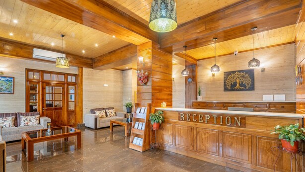 A reception area with wooden paneling, a reception desk, and a marble floor. - Summit Alpine Abode (Gangtok)
