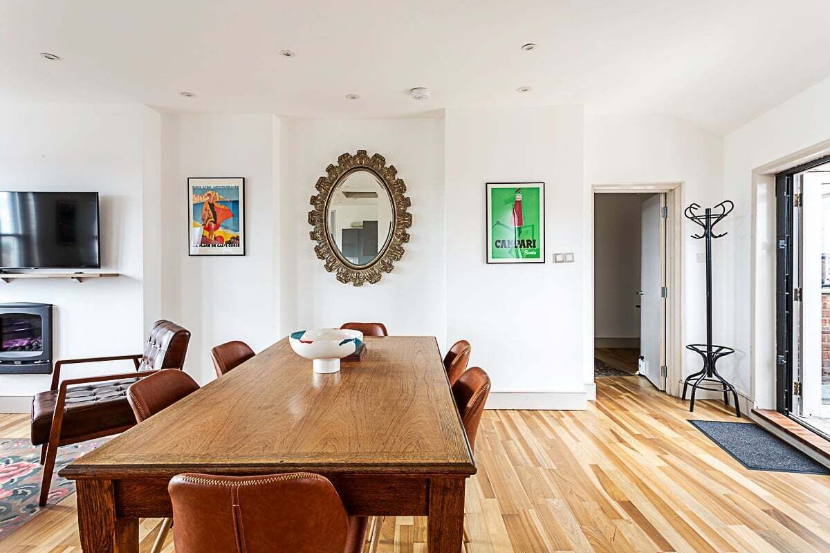 Un comedor con mesa de madera, sillas, televisor y obras de arte en las paredes.