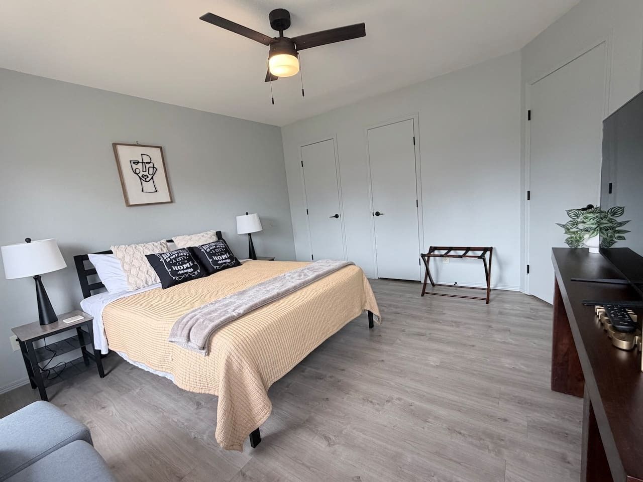 Ein modernes Schlafzimmer mit Bett, Nachttischen, Schreibtisch und Deckenventilator.