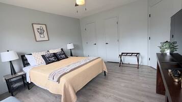 Ein modernes Schlafzimmer mit Bett, Nachttischen, Schreibtisch und Deckenventilator.