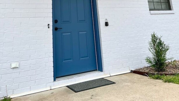 Um prédio branco com porta azul, uma janela pequena e uma caixa de correio.