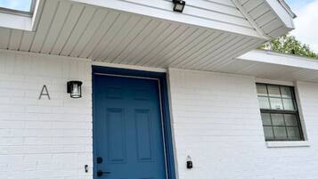 A white building with a blue door, a small window, and a mailbox.