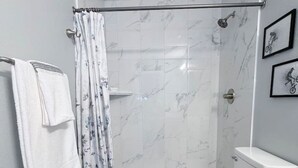 Casa de banho moderna com chuveiro, sanita e um porta-toalhas.