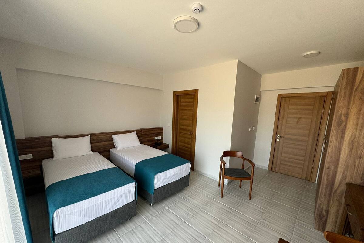 A hotel room with two beds, a chair, and wooden doors.