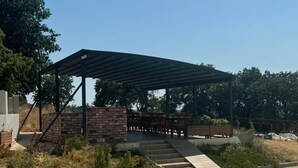 A covered outdoor seating area with a brick wall and wooden benches. - Troilus Park House Hotel (Eceabat)
