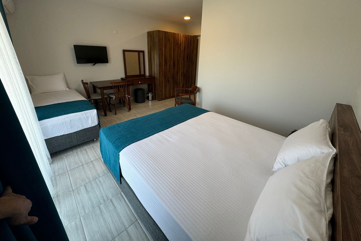 A hotel room with two beds, a desk, a chair, a television, and a wardrobe.
