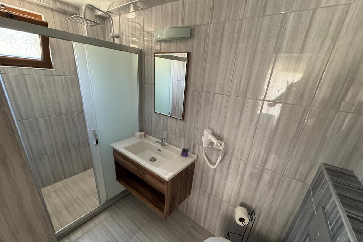 A modern bathroom with a shower, sink, and toilet.