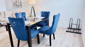 Een eethoek met een tafel, stoelen, een lamp en een schilderij aan de muur.