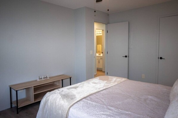A bedroom with a bed, a bedside table, and a door leading to a bathroom.