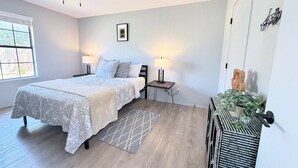 A bedroom with a bed, bedside tables, a ceiling fan, a window, and a wall-mounted plant. - Townhome, Walk to The Momentary and Trails (Bentonville)