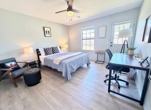 A bedroom with a bed, desk, chair, and a ceiling fan.