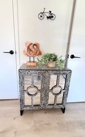 A small, black-framed, patterned side table with a wooden sculpture and a potted plant. - Townhome, Walk to The Momentary and Trails (Bentonville)