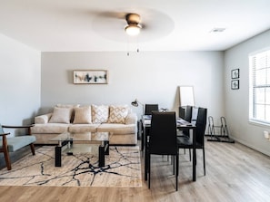 A modern living room with a sofa, coffee table, and dining area.