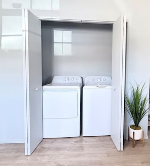 A laundry room with two white dryers and a potted plant. - Townhome, Walk to The Momentary and Trails (Bentonville)