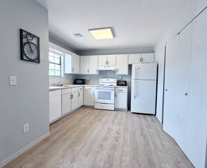 A modern kitchen with white cabinets, a stove, microwave, and refrigerator.