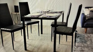 A dining area with a table set for four, surrounded by black chairs.