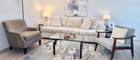 Una sala de estar con un sofá, dos sillones, una mesita de centro y una lámpara de pie.